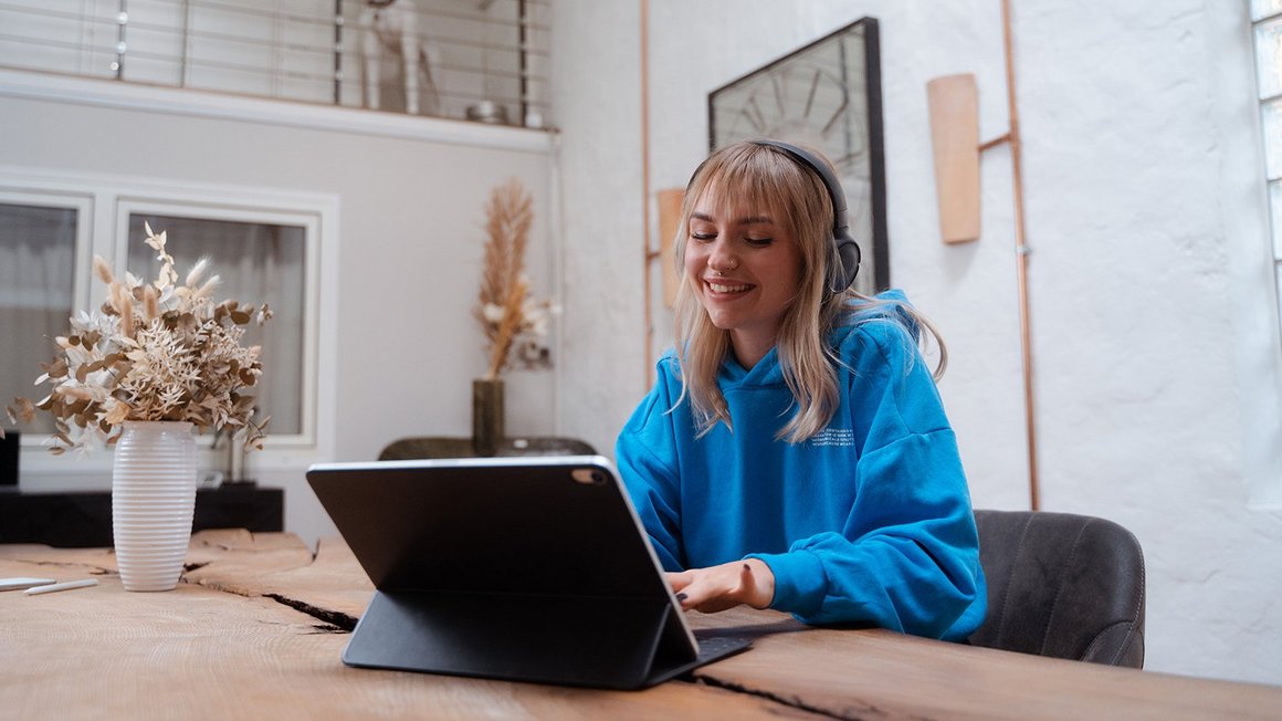 Künstliche Intelligenz Mitarbeiterin mit Headset und Tablet am Tisch