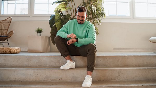 4. Pausen einplanen Mann sitzt auf der Treppe und schaut lachend auf die Uhr