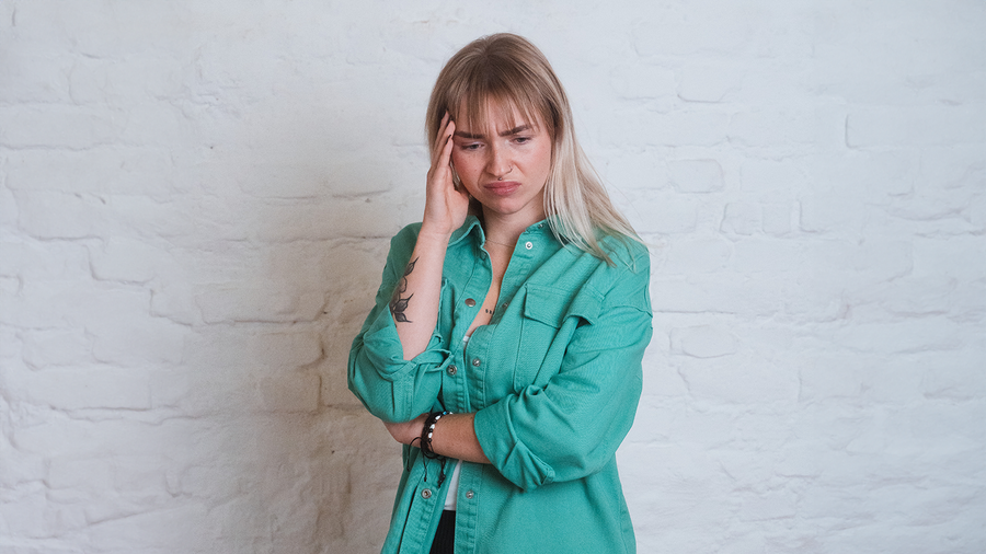 Krank zur Arbeit: Präsentismus durch eine resiliente Unternehmenskultur vermeiden Frau hält sich die Hand an den Kopf
