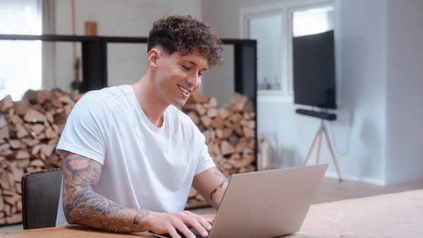 Berufliche Neuorientierung: 6 Schritte zum Neuanfang Junger Mann arbeitet am Laptop und ist zufrieden nach beruflicher Neuorientierung