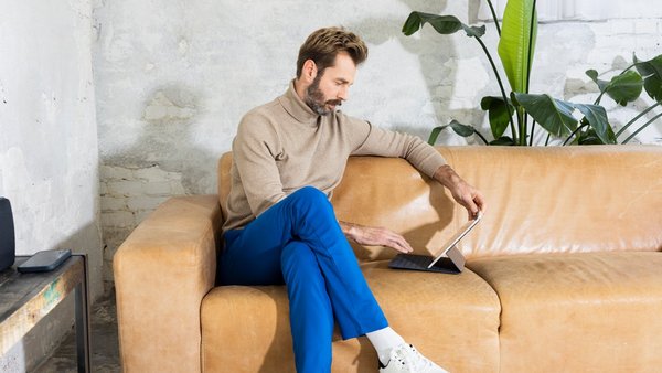 Man works with tablet on the couch – Work-life integration    Man works with tablet on the couch – Work-life integration