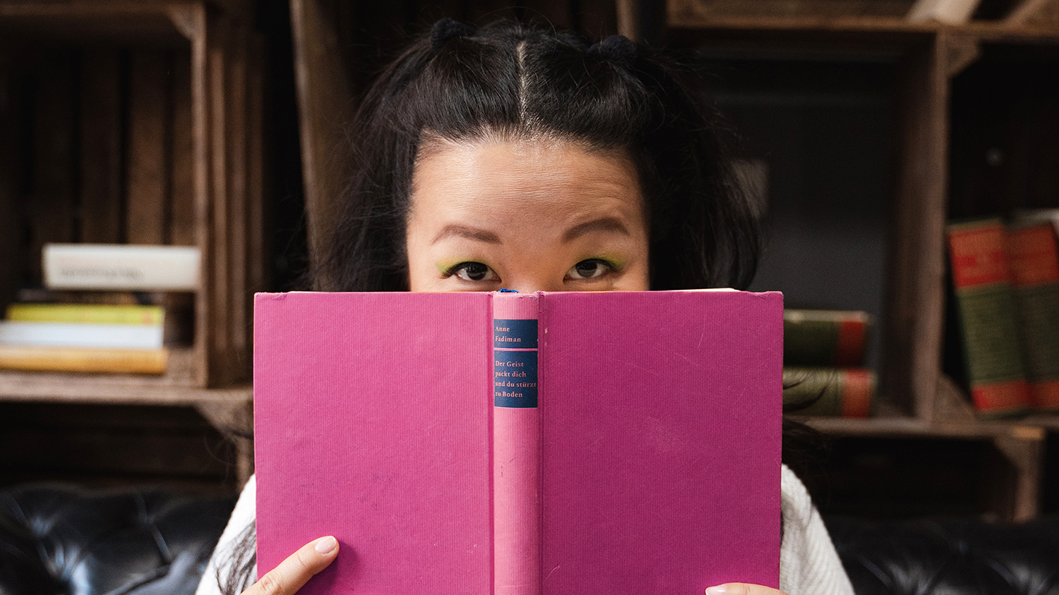 Young woman holding a book in front of her face
