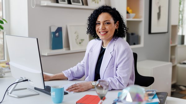 Public Relations Frau am Tisch lächelt in die Kamera.