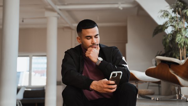 Stellenangebote. Mann schaut nachdenklich auf sein Handy.