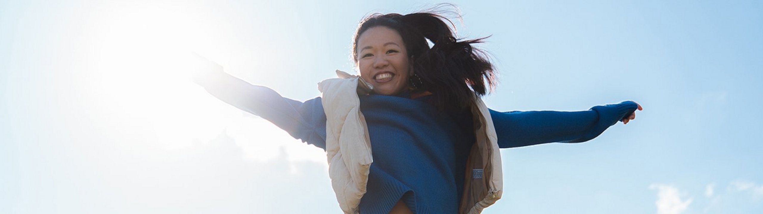Our multifaceted commitment Woman jumps into the sky with outstretched arms