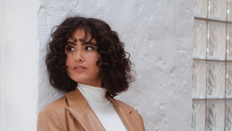 Junge Frau lächelt und lehnt sich an einer Wand an